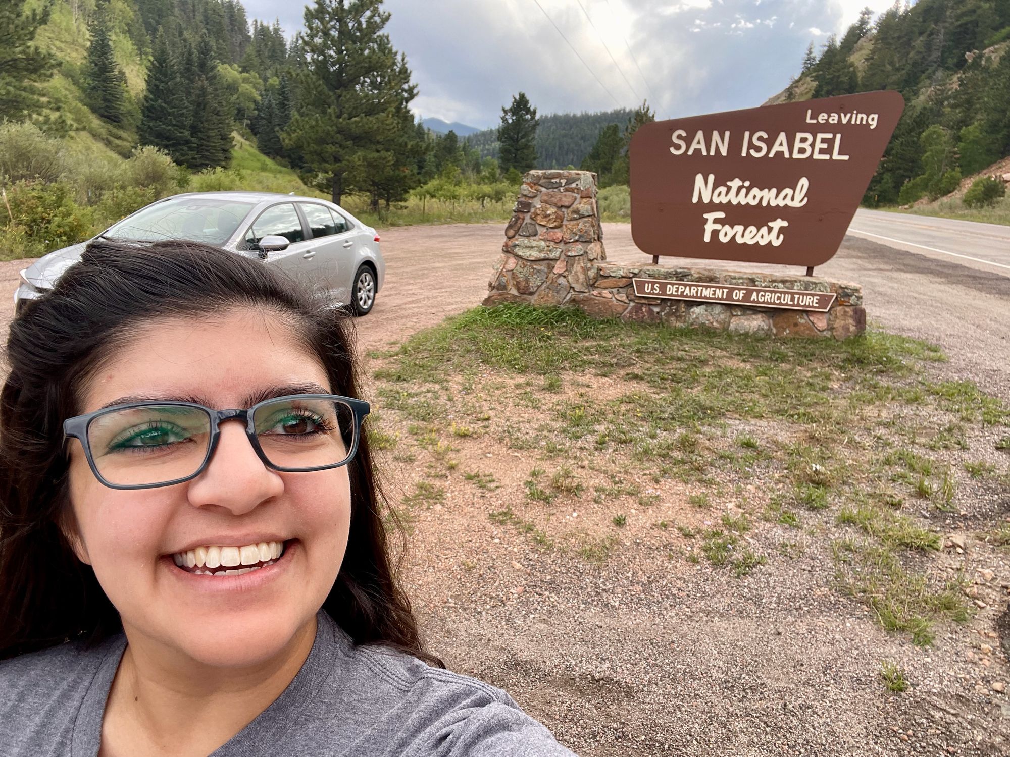 Meera posing in front of the "Leave San Isabel National Forest" sign.