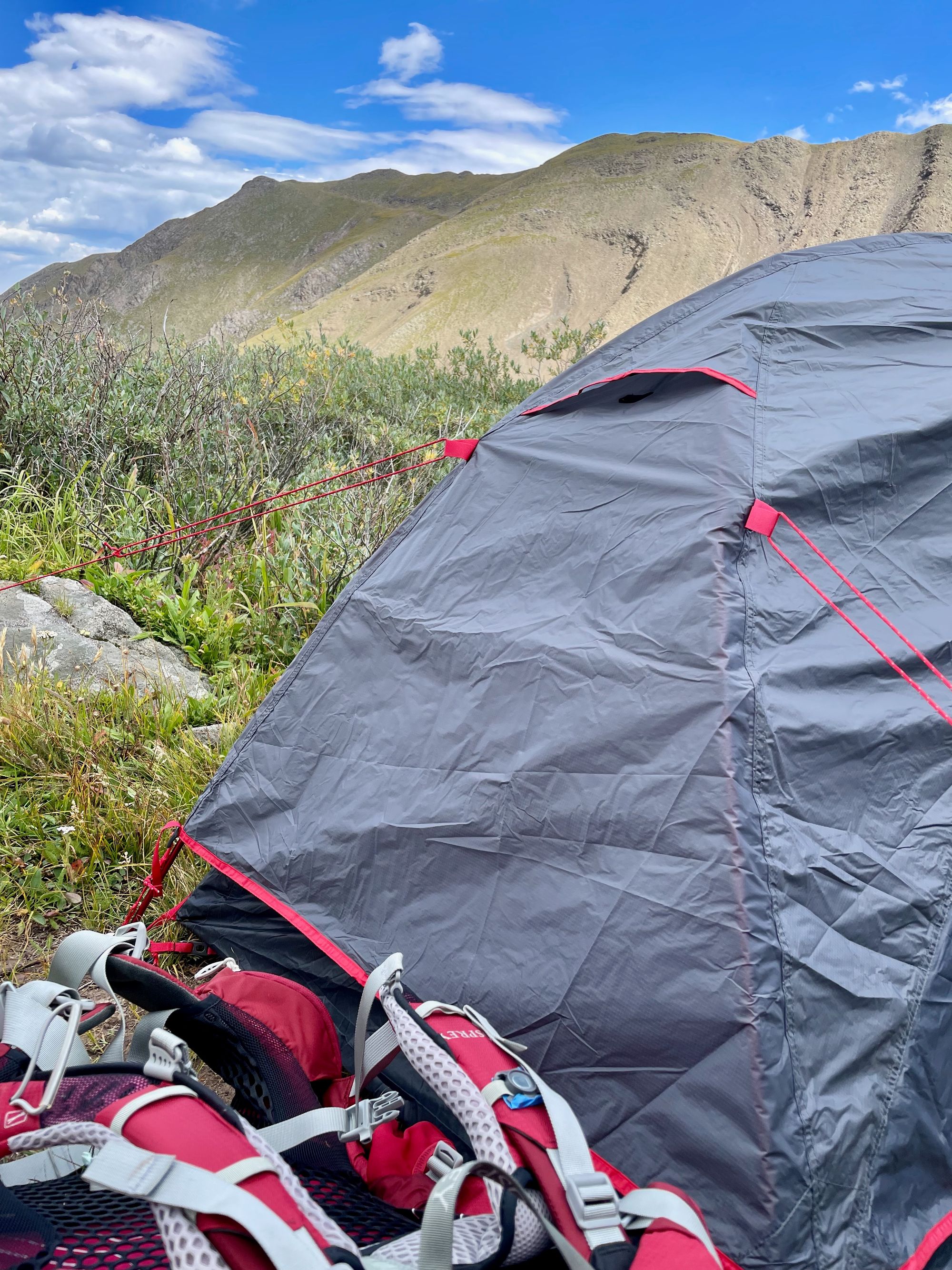Backpack and tent in foreground; mountains behind.
