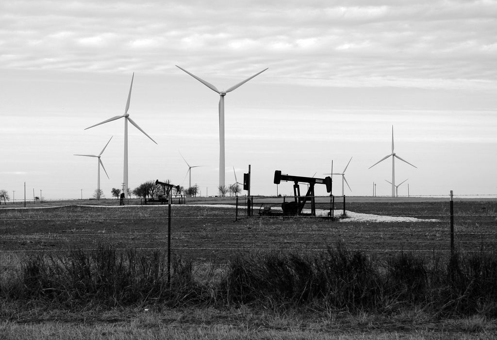 West Texas wind farms in the background and oil derricks in the foreground.