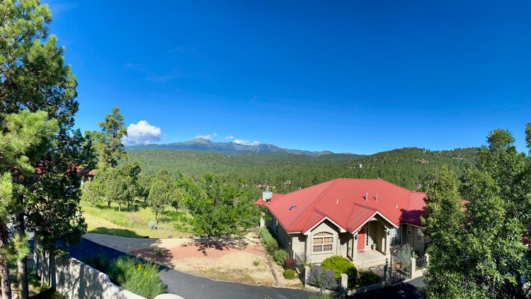 A New Mexico mountain in the background behind a neighborhood house with a red roof.