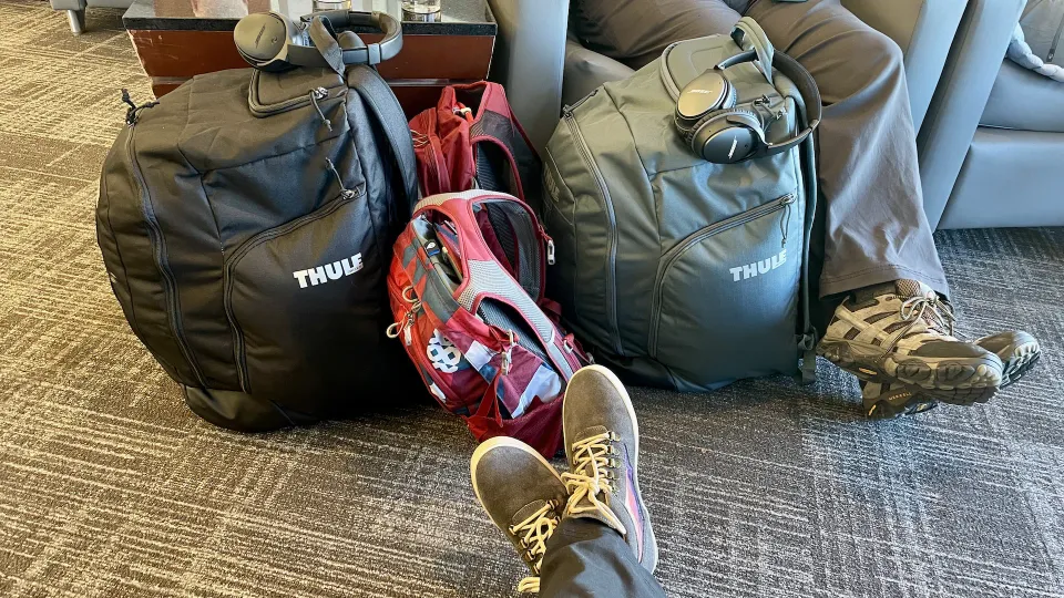 Ski boot bags, backpacks, and headphones in the Admiral's Club at Charlotte Douglas International Airport.